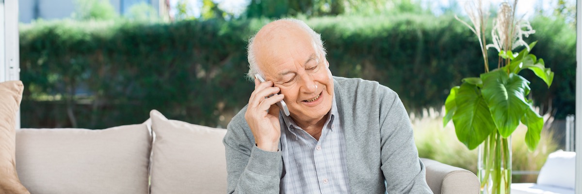 An older white haired man sits on a sofa, smiling and chatting on a mobile phone. Erin International can assist in helping to trace any pre-retirement pension members or their next of kin if necessary